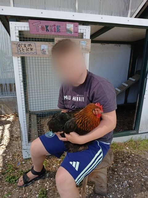 Een jongen houdt trots een kip vast